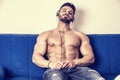 Male bodybuilder listening to music on sofa Royalty Free Stock Photo