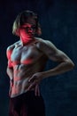 Handsome shirtless young guy with relief, muscular, fit body shape standing shirtless against dark textured studio Royalty Free Stock Photo