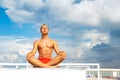 Handsome Shirtless Young Man During Meditation or Doing an Outdoor Yoga Exercise Sitting against the blue sky. Royalty Free Stock Photo