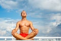 Handsome Shirtless Young Man During Meditation or Doing an Outdoor Yoga Exercise Sitting against the blue sky. Royalty Free Stock Photo