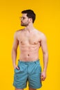 handsome shirtless young man in shorts and sunglasses standing with hand in pocket and looking away Royalty Free Stock Photo