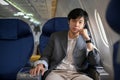 Handsome and smart Asian businessman on the plane, at the window seat in a business class Royalty Free Stock Photo