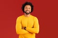 Handsome smiling African American curly young man in casual wear posing on red background Royalty Free Stock Photo