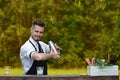 Handsome smiling barman shaking and mixing cocktail outdoors, ca