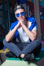 Handsome blond young man in blue sunglasses, sitting on stair Royalty Free Stock Photo