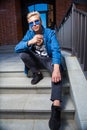 Handsome blond young man in blue sunglasses, sitting on stair st Royalty Free Stock Photo