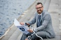 handsome smiling businessman in grey suit reading newspaper on quay Royalty Free Stock Photo