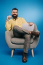 Handsome smiling businessman sitting in armchair with laptop Royalty Free Stock Photo