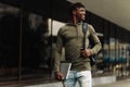 Handsome smiling dark-skinned student, wearing glasses with a backpack, holding a laptop, walking around the campus Royalty Free Stock Photo