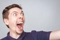 Handsome smiling excited man shout, posing on light studio background. Happy or angry young man in casual clothes can`t believe