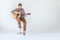 Handsome smiling guitarist play music siting on chair