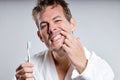 handsome smiling guy brushing tooth, wearing bathrobe, isolated on gray studio background Royalty Free Stock Photo