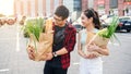 Handsome smiling guy in glasses and cute slender girl go with two big paper bags full of various products purchased in