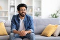 Handsome Smiling Indian Man Sitting On Couch At Home And Looking Away Royalty Free Stock Photo