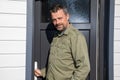 handsome smiling man bearded posing front grey door home property outdoors