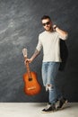 Handsome smiling man with guitar posing in studio