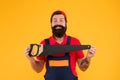 Handsome smiling man happy with saw yellow background. Gardener lumberjack equipment. Tools shop. Sharp blade of saw