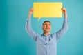 Handsome smiling man holding blank speech bubble sign isolated on light blue studio banner background with copy space Royalty Free Stock Photo