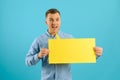 Handsome smiling man holding blank speech bubble sign isolated on light blue studio banner background with copy space Royalty Free Stock Photo