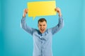 Handsome smiling man holding blank speech bubble sign isolated on light blue studio banner background with copy space Royalty Free Stock Photo