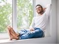 Handsome smiling man relaxing on window sill Royalty Free Stock Photo