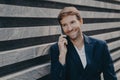 Handsome smiling man in stylish speaking on smartphone outside, enjoying conversation Royalty Free Stock Photo