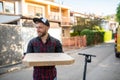 A handsome smiling pizza delivery man is standing on the street holding a box in his hands Royalty Free Stock Photo