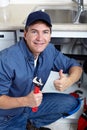 Smiling plumber repairs a sink.