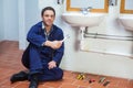Handsome smiling plumber sitting next to sink holding wrench Royalty Free Stock Photo