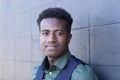 A handsome smiling young black man leans against a gray concrete block wall Royalty Free Stock Photo