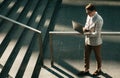 Handsome smiling young business man spending time outdoors at the city, using laptop computer on stairs Royalty Free Stock Photo