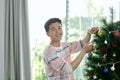 Handsome smiling young man decorating Christmas tree at his home Royalty Free Stock Photo