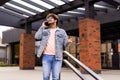 Handsome smiling young man dressed casually spending time outdoors at the city, talk mobile phone while walking down stairs Royalty Free Stock Photo