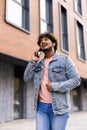 Handsome young man dressed casually spending time outdoors at the city, using mobile phone while walking down stairs Royalty Free Stock Photo