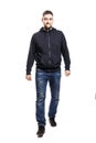 A handsome smiling young man in a hoodie and jeans is walking forward and looking at the camera. Full height. Isolated over white Royalty Free Stock Photo