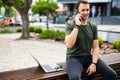 Handsome smiling young man sitting on a bench and talking on mobile phone Royalty Free Stock Photo