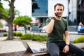 Handsome smiling young man sitting on a bench and talking on mobile phone Royalty Free Stock Photo