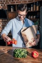 handsome smiling young man unpacking vegetables Royalty Free Stock Photo