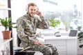 handsome soldier in headphones listening music and sitting on kitchen countertop