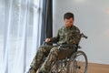 Handsome soldier sitting in a wheelchair on gray background