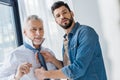 Handsome son helping cheerful retired father tying blue tie