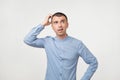 Handsome spanish guy in blue shirt, frowning and looking unsatisfied while scratching head Royalty Free Stock Photo