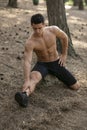 Handsome sportsman doing stretching exercises with legs in the park. Healthy lifestyle concept. Vertical view Royalty Free Stock Photo