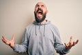 Handsome sporty bald man with beard wearing sweatshirt standing over pink background crazy and mad shouting and yelling with