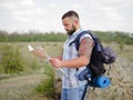 Strong bearded hiking guide looking at the map on a natural background. Hiking concept. Copy space.