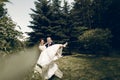 Handsome strong groom holding happy bride in the air, newlywed couple posing in summer park, groom carrying beautiful bride, Royalty Free Stock Photo