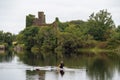 Handsome strong man rowing single scull. Water sport and active lifestyle concept. Menlo castle in the background