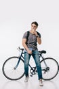 handsome student drinking coffee and leaning on bicycle