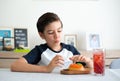 A handsome student schoolboy 8-9 years old wearing black glasses having snack Royalty Free Stock Photo