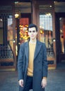 Handsome stylish fashionable man, brunette in elegant gray coat, stands on street in historical center of St. Petersburg. Young Royalty Free Stock Photo